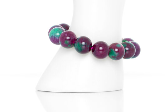 Ruby Zoisite bracelet on a white display stand. Collection of natural gemstones accessories. Studio shot