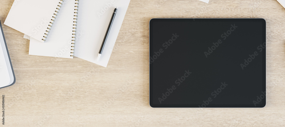 Poster tablet with blank screen is on top of wooden office desk table with supplies, above view. mock up, 3