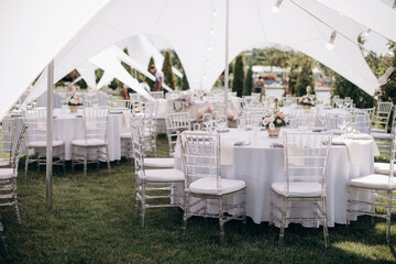 banquet table setting under a white tent on the grass