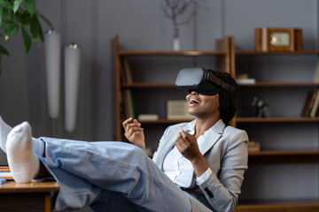 Impressed amazed african american female freelancer trying VR headset at first time to relax after working day from home, excited black woman shocked how virtual reality could improve remote work
