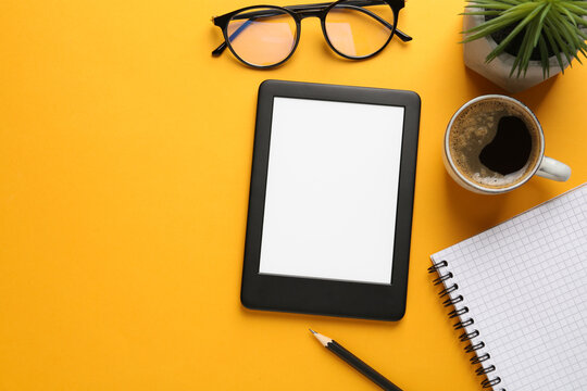 Flat lay composition with modern e-book reader on orange background, space for text