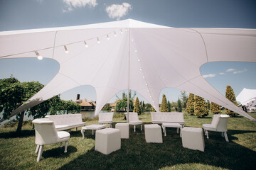 banquet table setting under a white tent on the grass