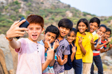 focus on front kid, Group of cheerful kids taking selife on hill top after successful completion of trek - concept of summer adventure,weekend activities, friendship and happiness.