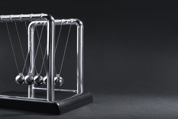 Fototapeta na wymiar Newton's cradle on dark background, space for text. Physics law of energy conservation