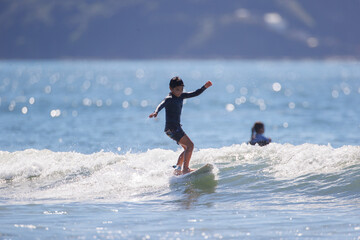 湘南の海でサーフィンをする少年 - obrazy, fototapety, plakaty