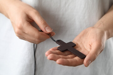 Woman holding wooden Christian cross, closeup view