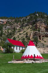 Vertical view of a small church and a red teepee in a field in 
Wyoming