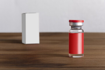 Closeup shot of a medical vial for injection with empty red label and white box on a wooden shelf