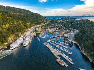 Aerial shot of the city, dense forest and moored boats and ferries at the harbor of Horseshoe Bay