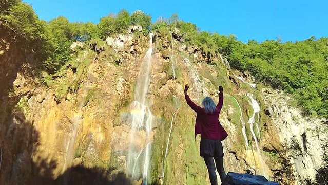 SLOW MOTION: Woman under the Veliki slap waterfall of Plitvice Lakes National Park in Croatia in the Lika region. UNESCO World Heritage of Croatia named Plitvicka Jezera.