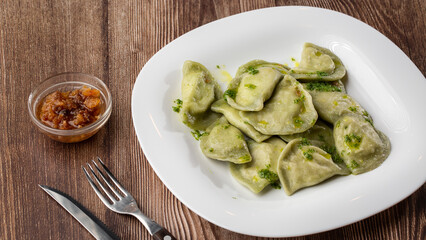 Traditional ukrainian dish vareniki served in a bowl with greaves and basil sauce. Close up view of traditional Ukrainian food.