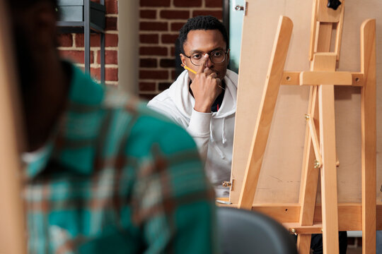 Portrait of young artist man looking at vase sketching model using drawing graphic pencil. Team of creative students learning sketch technique creating modern artwork on canvas. New years resolutions