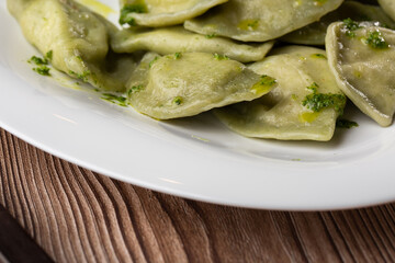 Traditional ukrainian dish vareniki served in a bowl with greaves and basil sauce. Close up view of...