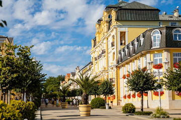 Frantiskovy Lazne, Western Bohemia, Czech Republic, 14 August 2021: Spa house or hotel on main street Narodni, White and yellow baroque historical building, town Franzensbad at sunny summer day