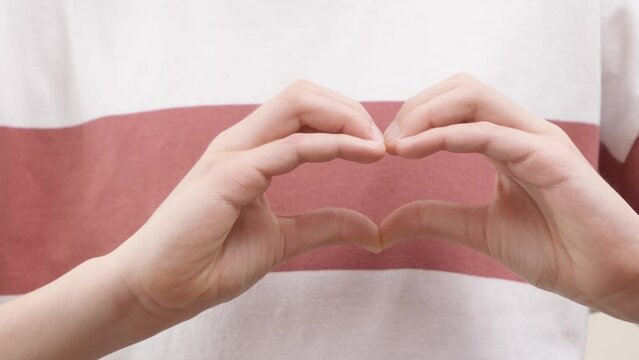 Hand gesture. Person showing heart with his hands. Boy arms in shape of symbol of love gesture. Close up. 4k footage
