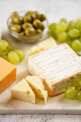 Cheese platter with organic cheeses - blue cheese cheddar, emmantaler, french soft cheese with strong smell, italian parmesan, grapes, tomatoes, olives, nuts and crackers on marble board