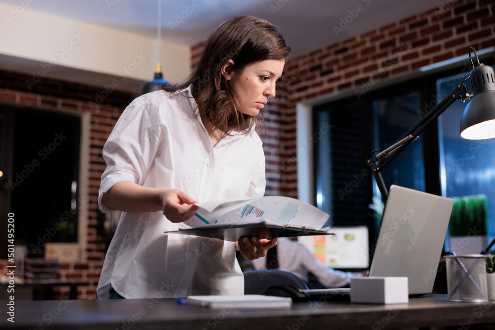 Poster marketing company employee in office workspace with documentation clipboard reviewing management cha