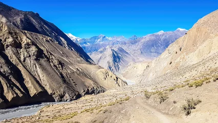 Cercles muraux Dhaulagiri A view on a dry bottom of Himalayan valley. The valley is located in Mustang region, Annapurna Circuit Trek in Nepal. In the back there is snow capped Dhaulagiri I. Barren and steep slopes