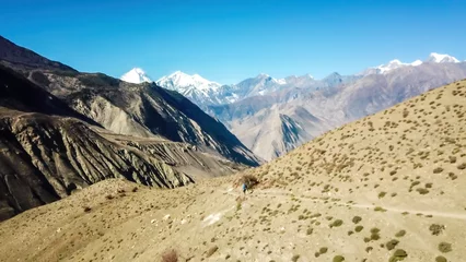 Papier Peint photo Dhaulagiri A panoramic view on dry Himalayan landscape. Located in Mustang region, Annapurna Circuit Trek in Nepal. In the back there is snow capped Dhaulagiri I. Barren and steep slopes. Harsh condition.