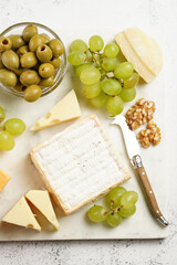 Cheese platter with organic cheeses - blue cheese cheddar, emmantaler, french soft cheese with strong smell, italian parmesan, grapes, tomatoes, olives, nuts and crackers on marble board