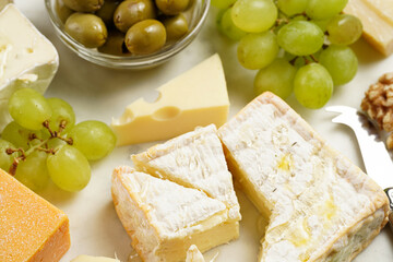 Cheese platter with organic cheeses - blue cheese cheddar, emmantaler, french soft cheese with strong smell, italian parmesan, grapes, tomatoes, olives, nuts and crackers on marble board