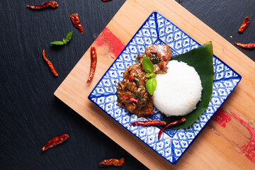 Asian Food concept Thai holy Basil Beef Stir Fry and Jasmine Rice Khao Pad Pad Kra Pow Nua in Thai tradition ceramic plate on wooden board and black slate stone background with copy space