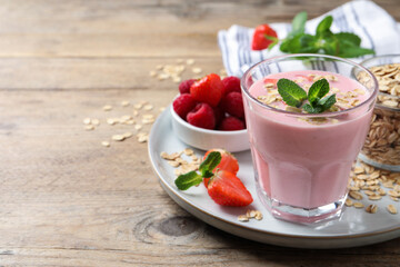 Glass of tasty berry smoothie with oatmeal on wooden table. Space for text