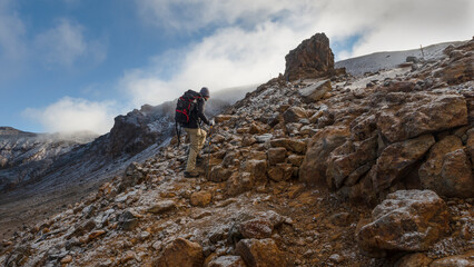 Hiking the steep scree terrain to the Red Crater summit on Tongariro Alpine Crossing. New Zealand.