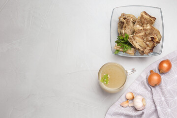 Delicious homemade bone broth and ingredients on light grey table, flat lay. Space for text