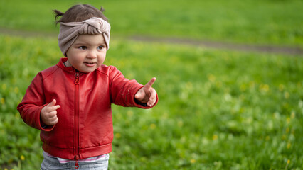 Portrait of a 2 year old girl. Girl in a red leather jacket and headband.
