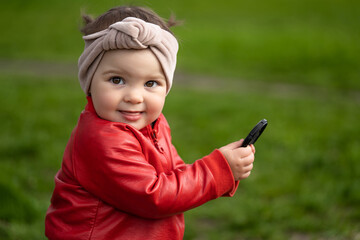 Portrait of a 2 year old girl. Girl in a red leather jacket and headband.