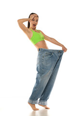 Diet concept and weight loss. Happy amazed woman in oversize jeans on white background