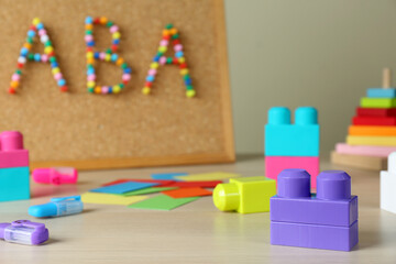 Cork board with abbreviation ABA (Applied behavior analysis) at table, focus on colorful blocks