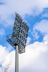 Huge pole of stadium light projectors against a sky