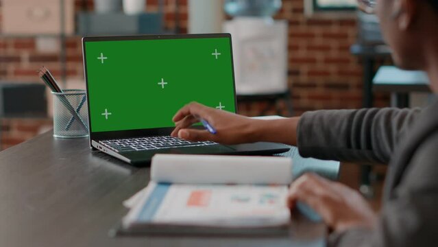 Man using greenscreen on laptop and taking notes at office job. Business employee working with mockup copyspace, isolated blank background and chromakey template on computer display.