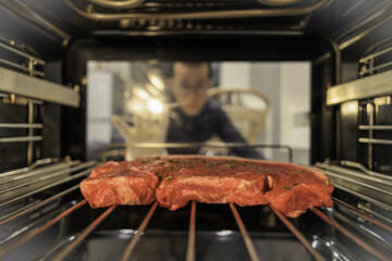 Close-up shot of a raw steak in the oven with a blurred background of the cook