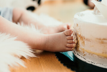 Close-up shot of a cute baby toes messing a white cake