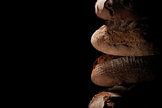 Closeup of fresh-baked loaves stacked on top of each other against a black background