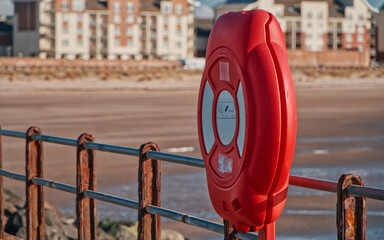Closeup of a red lifebuoy in front of a metal railing in Ayr, Scotland