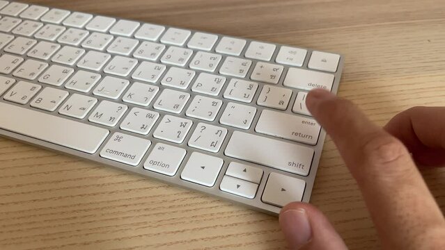 Typing on keyboard. Male hand fingers pressing "return" button key on English - Thai computer white keyboard close up. Work from home professional hand press enter button key on keyboard