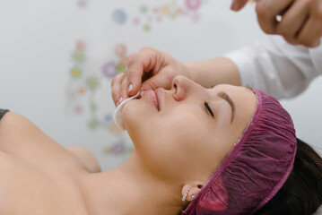 Top view of cosmetologist removing peeling mask from female face