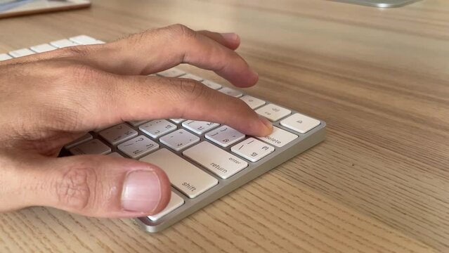 Typing on keyboard. Male hand fingers pressing "delete" button key on English - Thai computer white keyboard close up shot. Work from home professional hand press backspace button to delete text
