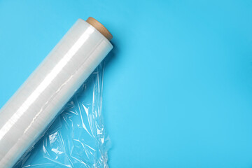 Roll of transparent stretch wrap on turquoise background, top view. Space for text