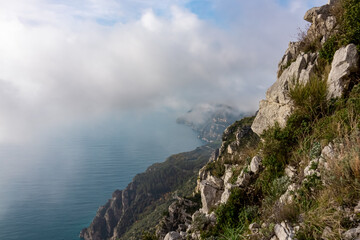 Aerial view from a hiking trail on cloudy coastal driving road of the beautiful scenic Amalfi Coast, Campania, Italy, Europe. Riviera coastline at Mediterranean sea. Panoramic curvy road near Positano