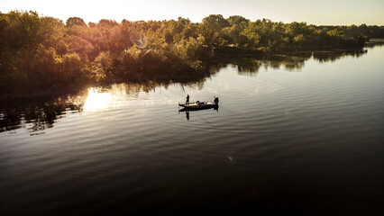 Aerial view of a fisherman with a fishing boat in the middle of the lake Grand, Oklahoma at sunset - obrazy, fototapety, plakaty