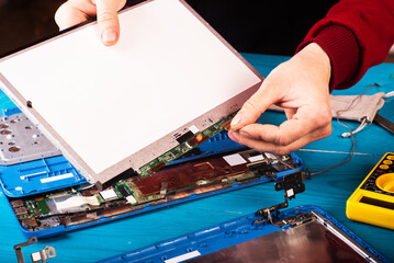 Wizard repairs laptop with tools and hands on the blue wooding table. top view