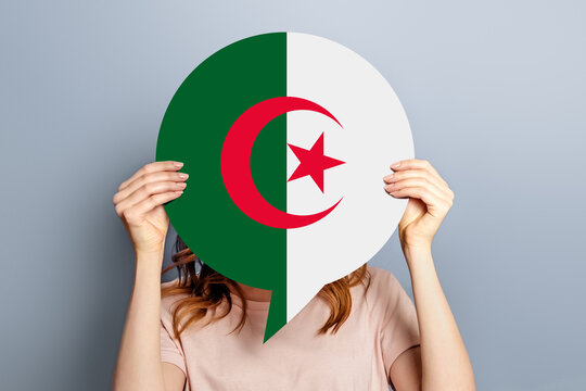 Algeria news concept. Female hands holding a round information poster with Algeria flag isolated over grey studio background