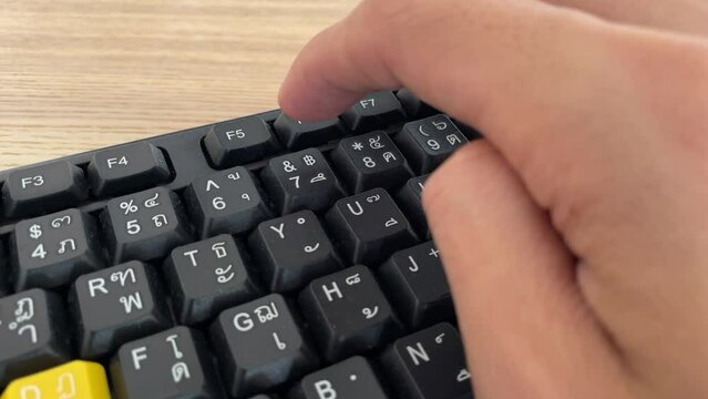 Typing on keyboard. Male hand fingers pressing F5 button key on English - Thai computer black keyboard close up shot. Work from home professional hand press F5 to reload and refresh the page browser