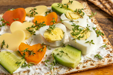 Matzah sandwich with cream cheese, fresh cucumber, bell pepper, boiled eggs, thyme leaves. Breakfast ideas for Jewish holiday Pesach.