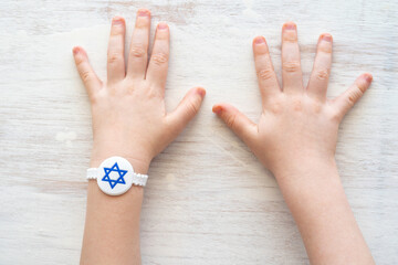 Child hand with bracelet for Independence Day of Israel on white wooden background.  Bracelet with...